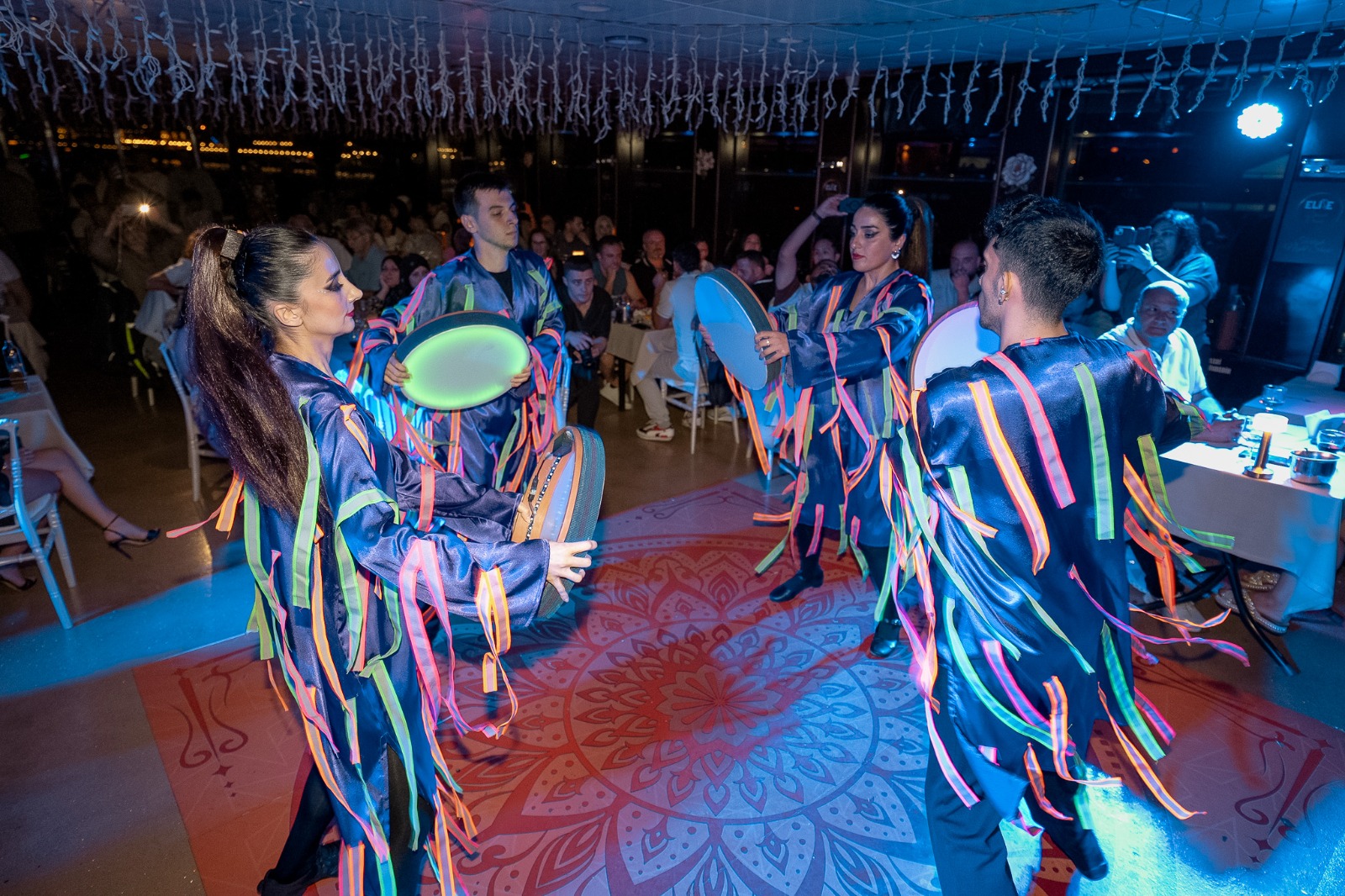 Guests seated at dinner tables on the Bosphorus cruise with stage entertainment in view